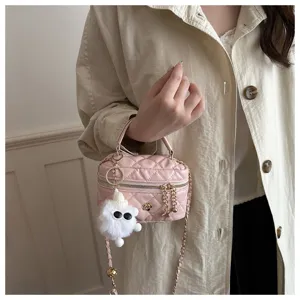 Detalle de bolso bandolera acolchado rosa con cadena dorada y colgante de peluche.