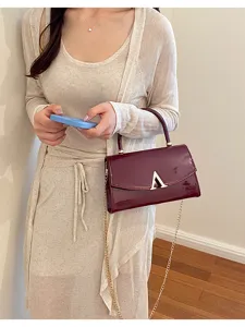 Elegante borsa a tracolla in pelle verniciata bordeaux con catena dorata e chiusura.