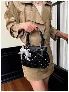 Detailed view of black velvet polka dot handbag featuring cute bow and elegant pearl pendant.