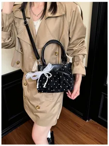 Black polka dot ruched crossbody bag with pearl ribbon detail, stylish daily commute choice.