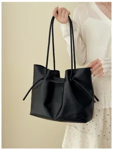Primo piano della borsa shopper in pelle PU nera con dettagli di tracolla e coulisse.