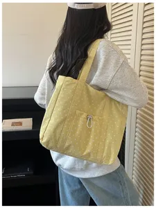 Vista dettagliata della borsa tote in tela a pois gialli, che mostra la tasca frontale e i dettagli.