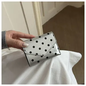 Detailed view of silver tri-fold wallet with black polka dots, sleek PU leather surface.