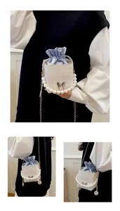 Close-up details of fashionable summer bucket bag featuring elegant pearl handle and chic bow.
