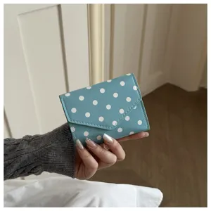 Close-up shot of a blue polka dot wallet showing fine leather texture and envelope flap.