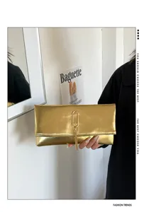 Vue de détail d'une pochette dorée métallisée avec un fermoir élégant et un joli pompon.