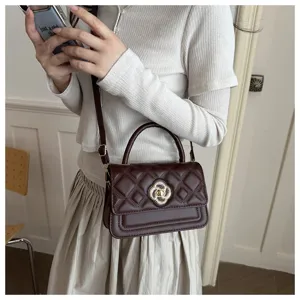 Detailansicht der schicken braunen gesteppten Handtasche mit Griff und goldenem Blumenschloss.