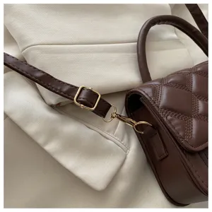 Detailaufnahme der braunen gesteppten Umhängetasche aus Leder mit schickem Gold-Beschlag und Riemen.