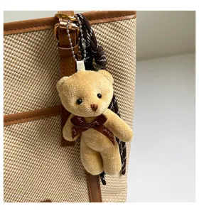 Detalle del bonito colgante de oso de peluche con lazo en el asa del bolso de lona.