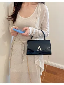 Borsa a tracolla da donna elegante in pelle verniciata con catena dorata e chiusura metallica.