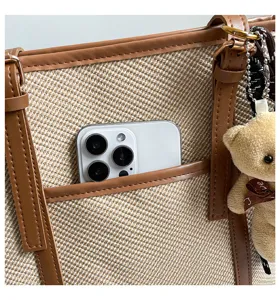 Detalle de bolso tote de lona con bolsillo frontal para smartphone y lindo colgante de oso.