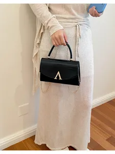 Borsa a spalla da donna in pelle verniciata nera con catena dorata e chiusura chic.