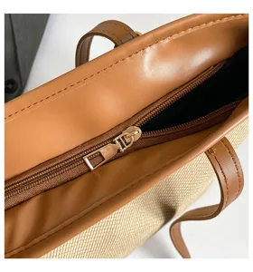 Vista detallada del bolso tote de lona elegante con ribete de cuero PU marrón y cierre de cremallera.