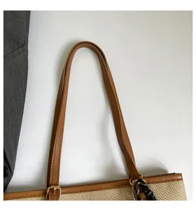 Vista de detalle del bolso tote de paja para mujer con asa de cuero marrón y diseño elegante.