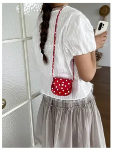 Süße rote Mini-Satteltasche mit Pünktchen im Detail, stylisches Umhängeaccessoire für Kinder.