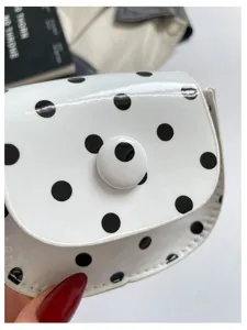 Detailaufnahme der weißen Mini-Satteltasche mit schwarzen Punkten und rundem Knopf.