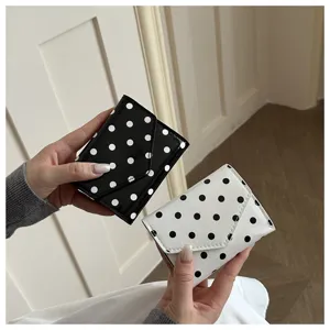 Polka dot short wallet detail showing black and white options held in hands clearly.