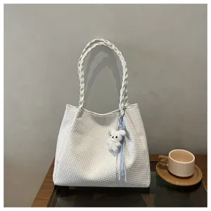 Detail view of a white woven tote shoulder bag with a cute plush charm for daily use.