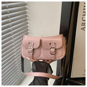 Vista dettagliata della borsa a spalla rosa con due tasche frontali e fibbie in metallo.