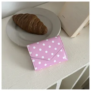 Dettaglio portafoglio rosa a pois, con grazioso design a pattina a busta e finitura lucida pelle.