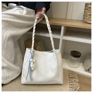 Detail view of the elegant white woven tote bag with braided handle and cute plush charm.