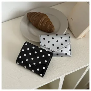 Detailed shot of trendy polka dot mini tri-fold wallets in black and silver finishes.