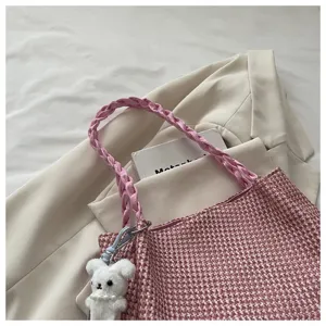 Pink woven shoulder bag detail view with cute plush bear pendant and braided strap design.