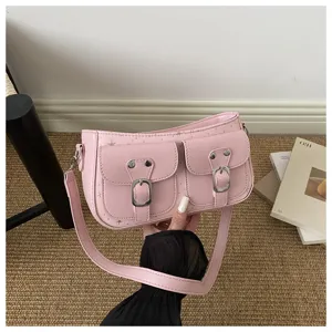 Detailansicht der rosa Umhängetasche mit zwei Vordertaschen und eleganten Metallschnallen.