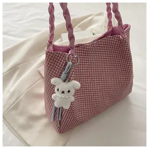 Stylish pink woven tote bag with braided handles and cute plush bunny keychain accessory.