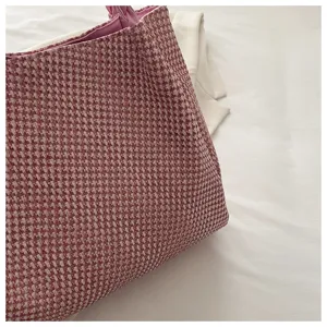 Woven tote bag detail showing pink textured fabric, shoulder strap and casual commuter style.