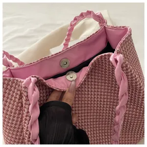 Pink woven tote bag detail showing magnetic snap closure and stylish braided shoulder straps.