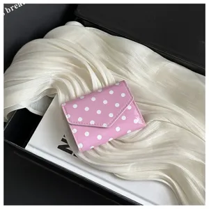 Pink polka dot wallet detail showcasing exquisite white dot pattern and glossy leather texture.