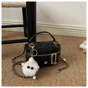 Bolso neceser acolchado negro con cadena y lindo colgante de peluche blanco, detalle.