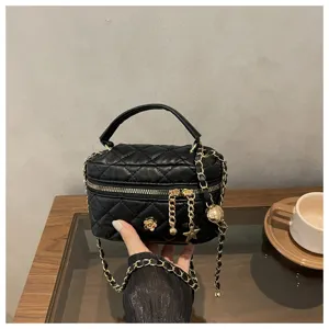 Detalle de mini bolso acolchado negro con correa de cadena y colgante de flor chic.
