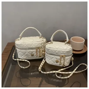 Vista detallada de un elegante bolso cruzado blanco acolchado con cadena y abalorio floral.