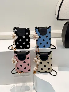 Vue détaillée de quatre sacs à bandoulière à pois colorés avec breloques fleurs et rabats.