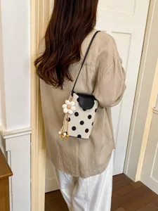Vue détaillée du sac bandoulière élégant pour femmes à pois avec pendentif fleur.