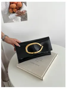 Zwarte lakleren enveloppe clutch tas met opvallende gouden C-vormige metalen gesp.