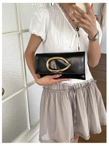 Minimalistische zwarte envelop clutch tas voor dames met opvallende gouden gesp detail.