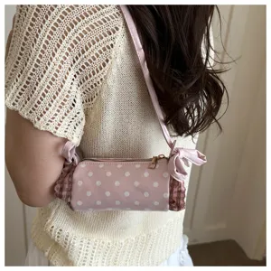 Borsa a tracolla cilindrica a pois rosa con volant a quadri, dettaglio di stile dolce.