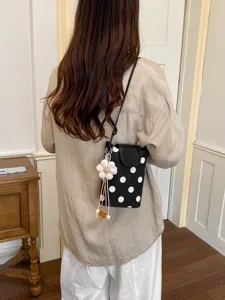 Détail du petit sac à bandoulière noir et blanc à pois avec un joli pendentif de fleur.