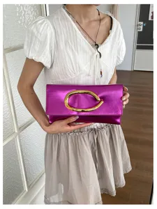 Detail van metallisch roze clutch, elegante dames avondtas met gouden C-vormige gesp.
