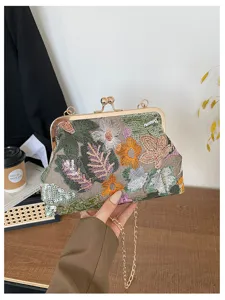 Dettaglio della borsa da sera ricamata con motivi floreali in paillettes e chiusura metallica dorata.