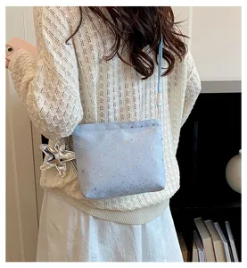 Close-up detail of the light blue crossbody bag with star pattern and silver star pendant.