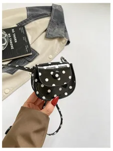 Nahaufnahme der süßen schwarz-weißen Pünktchen Lackleder Mini-Satteltasche Detail.