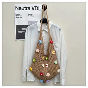 Vue détaillée d'un sac bandoulière au crochet marron avec fleurs colorées, style plage.