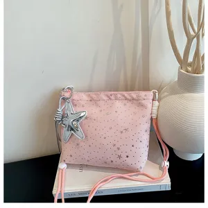 Pink crossbody bag detail featuring silver star prints and a large star charm pendant.