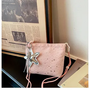 Close-up detail of the pink canvas crossbody bag featuring star print and silver star charm.