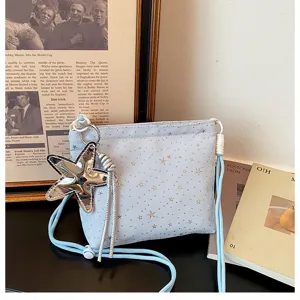 Detail shot of a light blue star print crossbody bag with a shiny metallic star pendant.