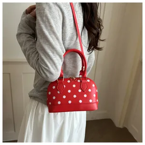 Detailed view of the red polka dot dome handbag, showing its elegant shape and strap.